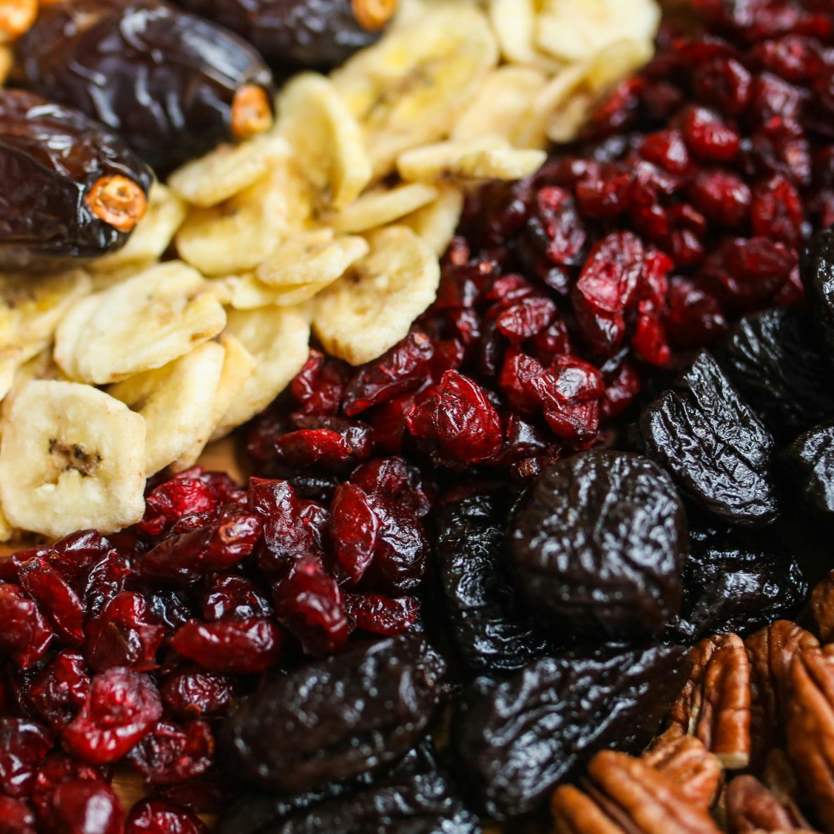 Vibrant mix of dried fruits and nuts on a wooden tray, perfect for healthy snacking.
